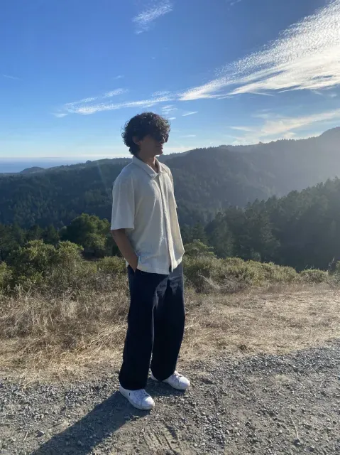 Samiel standing on a mountain ridge in daylight
