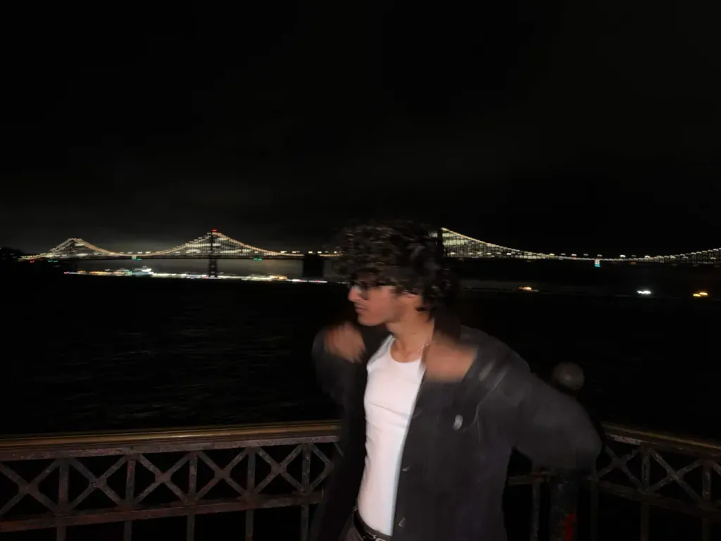 Samiel in motion beside a lit bridge at night