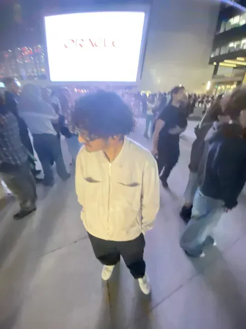 Samiel walking through a crowded outdoor event at night